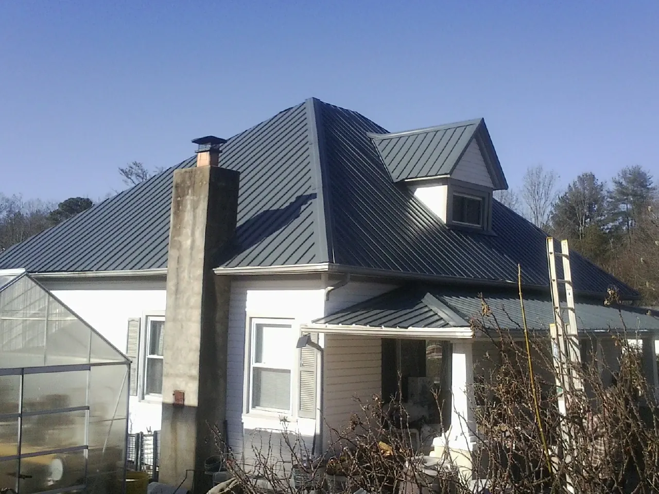Dark blue standing seam metal roof on a white farmhouse with dormer — Slate & Tile Roof Repair by Roofing Brothers in Elrama