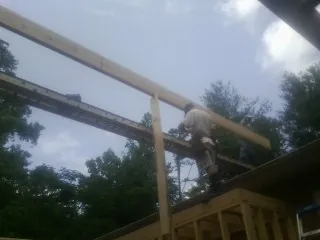 Carpenter setting a ridge beam over a new addition frame — Ice Dam Removal by Roofing Brothers in Elrama
