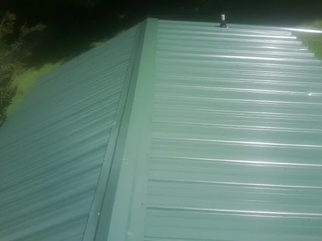 New green metal panels meeting at the ridge of a roof — Flat Roof Repair work by our crew in Elrama