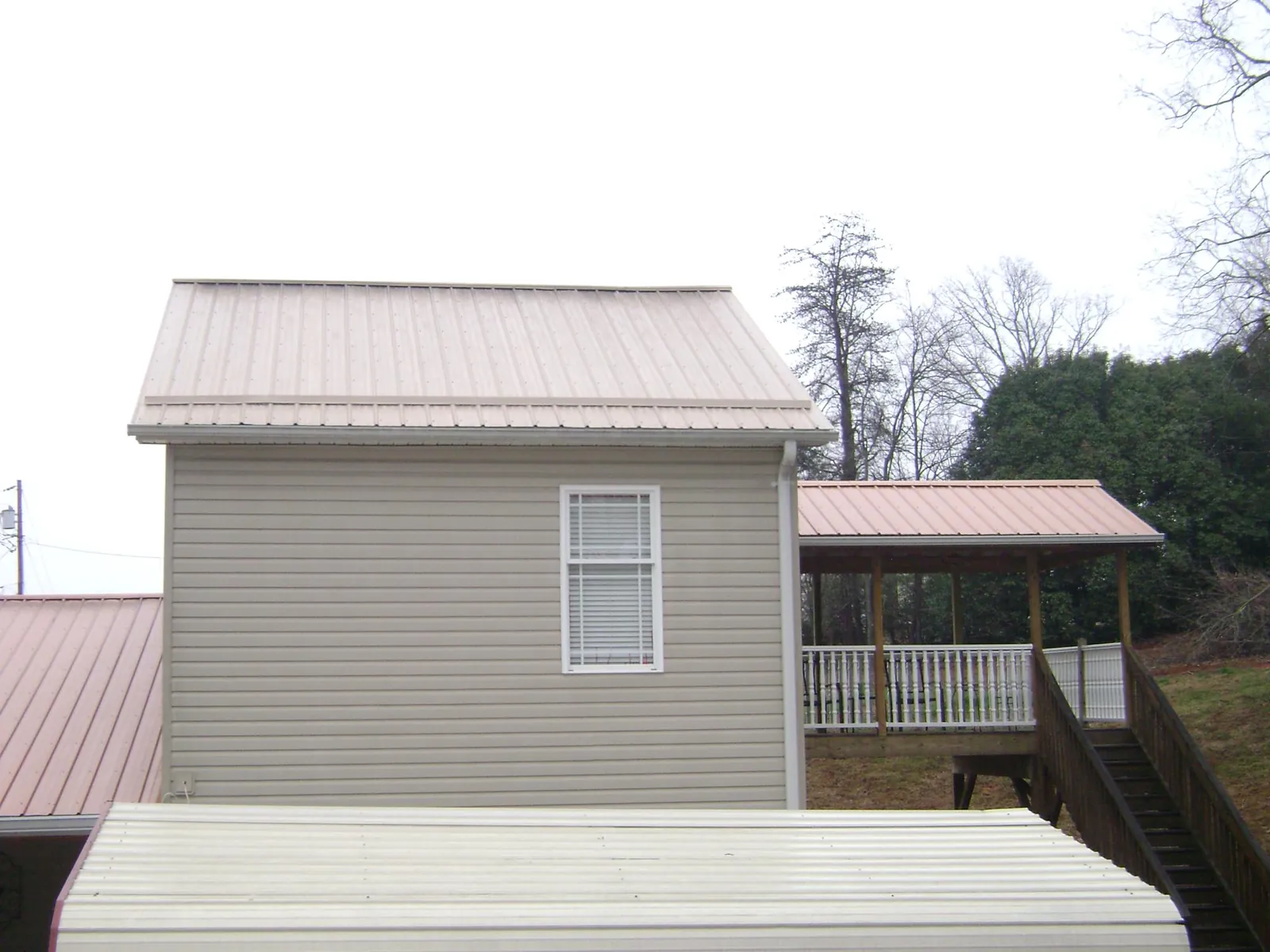 Tan metal roofs on a two story addition and attached porch, from a Roof Replacement job in Elrama