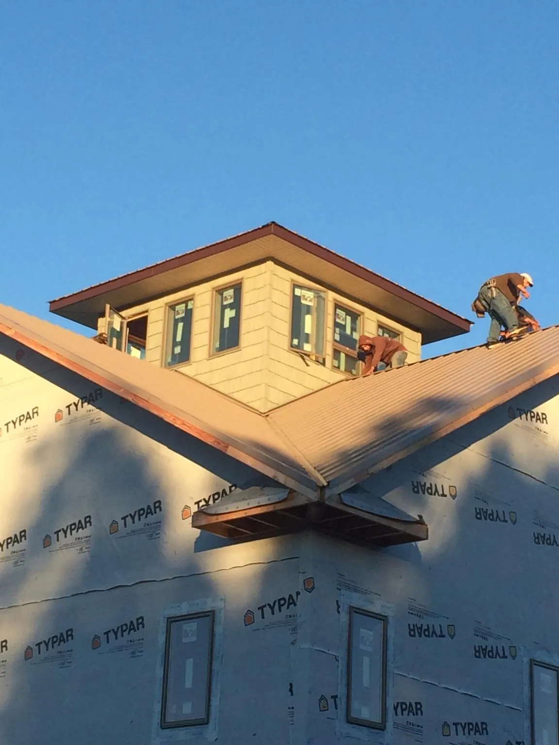 Roofers working around a rooftop cupola on a new metal roof at sunset — Roof Waterproofing in Elrama by Roofing Brothers